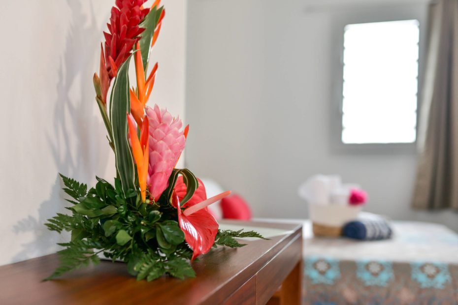 bouquet of tropical flowers and blue bungalow's bedroom in the background